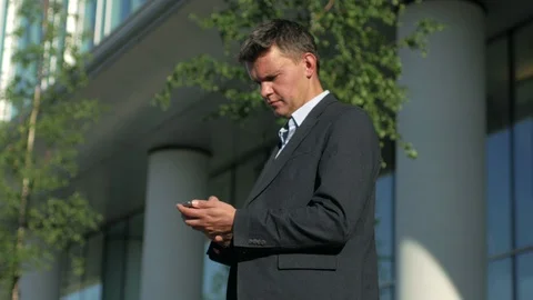 Businessman using app on smart phone near the office building Stock Footage 94078286
