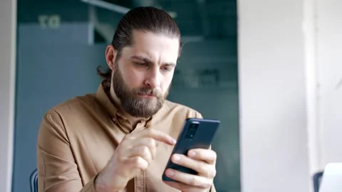 Businessman is using browsing mobile phone while sitting at desk at workplace  Stock Footage 308813916