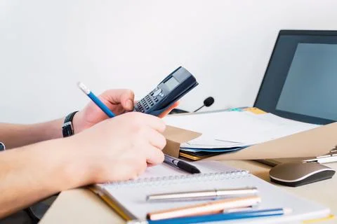 Businessman using a calculator and computer to note the data on the notepad - th Stock Photos