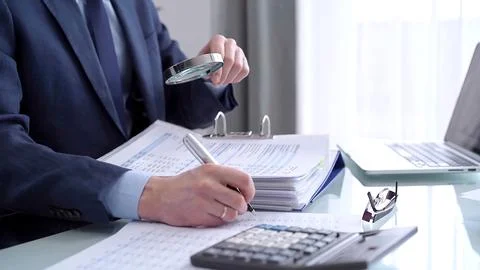 Businessman using a calculator and magnifying glass while analyzing financial 스톡 사진