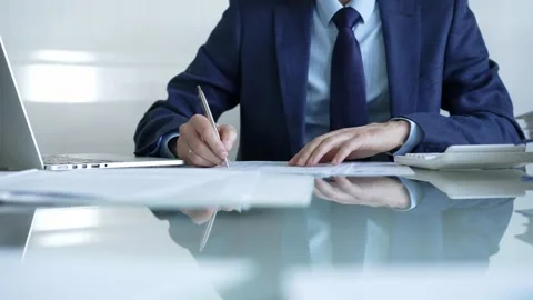 Businessman using calculator and taking notes, working with laptop and documents Stock Footage 305551395