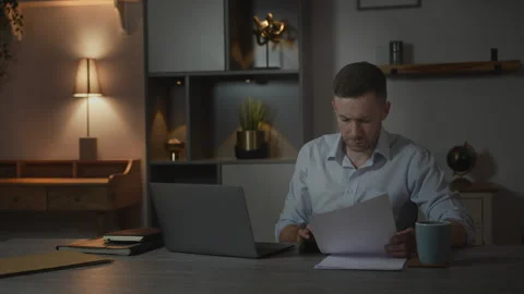 Businessman Using Calculator While Reviewing Financial Printout And Laptop Stock Footage 336407420