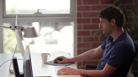 Businessman using computer and talking on mobile at office. Stock Footage 64104482