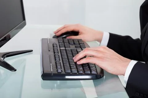Businessman using computer keyboard at desk Stock Photos