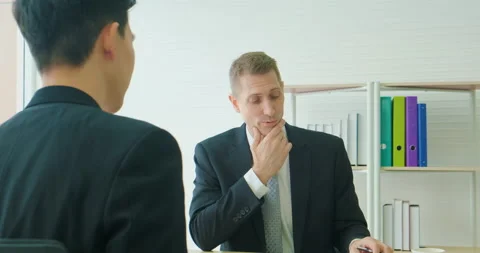 Businessman using a digital laptopo to discuss with a younger colleague Stock Footage 147111338