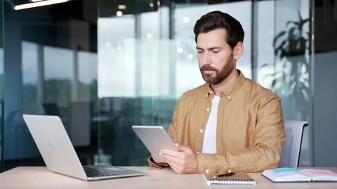 Businessman is using digital tablet sitting at workplace in business office.  Stock Footage 295039000