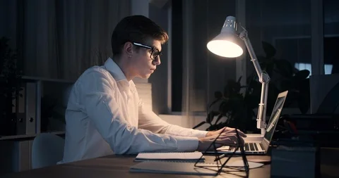 Businessman using laptop and analyzing document at night office Stock Footage 119179600