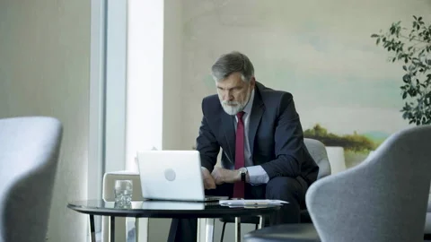 Businessman using laptop computer in office lobby or cafe. Video stock 250956787