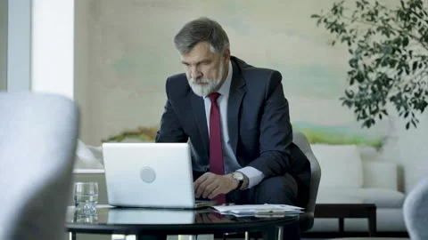 Businessman using laptop computer in office lobby or cafe. Video stock 250957537