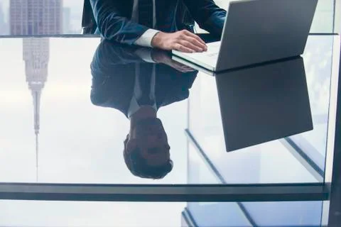 Businessman using laptop computer, reflection on glass top table 写真素材