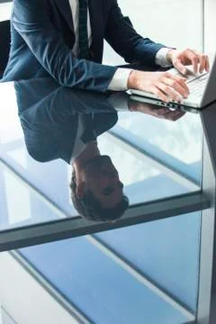 Businessman using laptop computer, reflection on glass top table Stock Photos