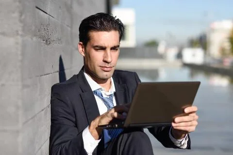 Businessman using a laptop computer sitting in the street Stock Photos
