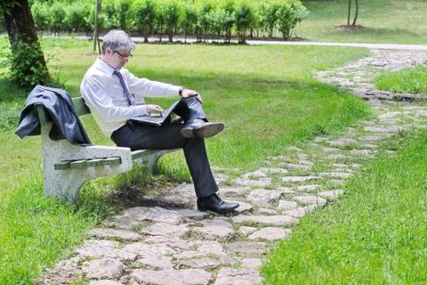 Businessman using laptop sitting on a bench Stock Photos