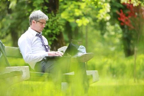 Businessman using laptop sitting on a bench Stock Photos