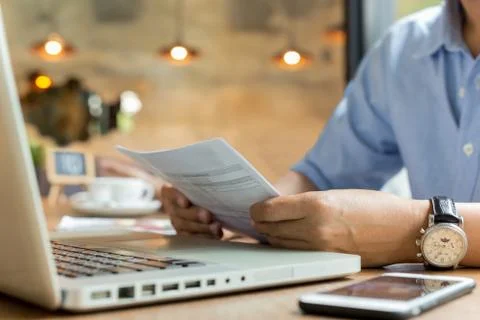 Businessman using laptop while looking at invoice. Stock Photos