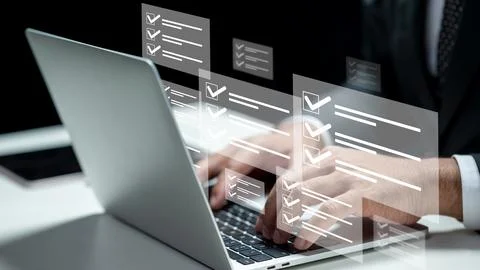 Businessman using a laptop while showing a questionnaire with a checkmark i.. Foto stock