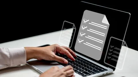 Businessman using a laptop while showing a questionnaire with a checkmark i.. Stock Photos