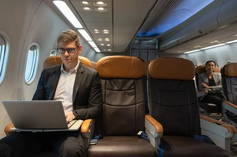 Businessman using laptop while sitting in airplane cabin Stock Photos