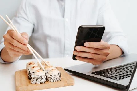 Businessman using mobile phone during lunch while sitting at table with lap.. Stock Photos