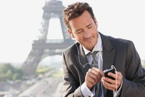 Businessman using a mobile phone with the Eiffel Tower in the background, Paris, 写真素材