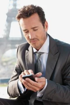 Businessman using a mobile phone with the Eiffel Tower in the background, Paris, 写真素材