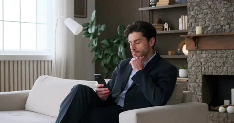 Businessman using mobile phone while sitting on sofa 스톡 동영상 239454337