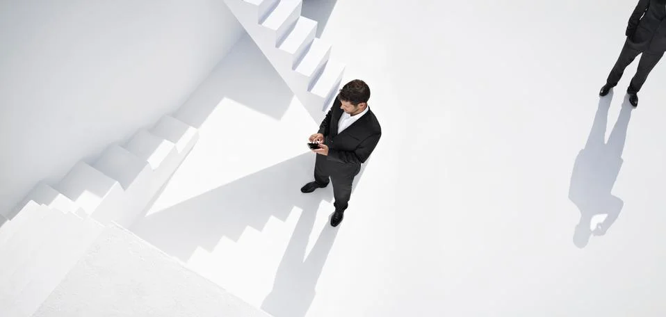 Businessman using mobile phone while another man standing behind Stock Photos
