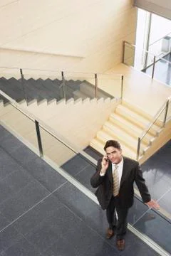 Businessman Using Mobile Phone While Standing By Glass Railing Stock Photos