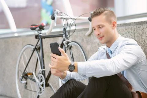 Businessman using mobile phone while sitting on the floor in city Stock Photos