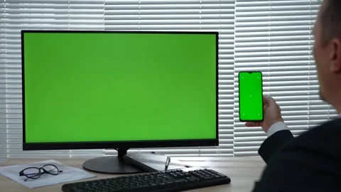 Businessman using phone and computer with green screen. Man using PC and sm.. Stock Footage 288855884