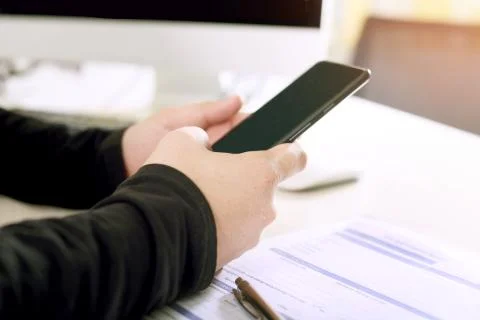 A businessman is using a phone with form while working on the desktop Stock Photos
