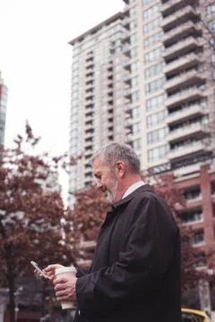 Businessman using smart phone while standing against building Fotos de archivo