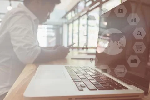 Businessman using smart phone while sitting with laptop on table at office wi Stock Photos