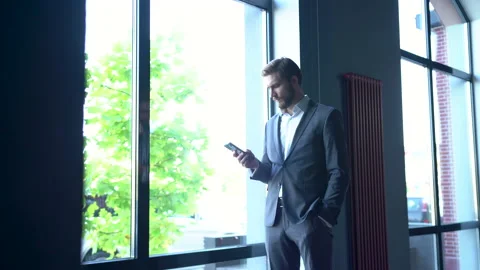 Businessman using smarthone. Young man texting Messages while standing in Office Stock Footage 171762006
