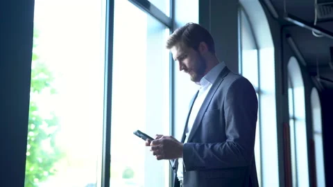 Businessman using smarthone. Young man texting Messages while standing in Office Stock Footage 171762032
