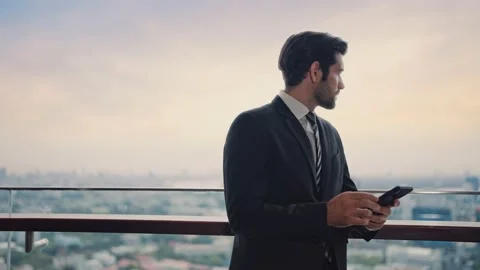 Businessman using smartphone and chatting online standing at the rooftop Stock Footage 214828165