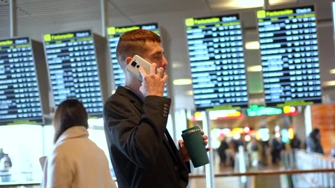 Businessman using smartphone and drinking coffee at airport Vidéo 302120804