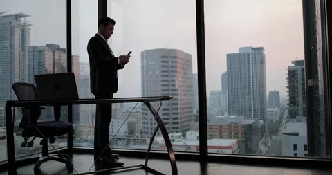 Businessman using smartphone in skyscraper office Stock Footage 99024432