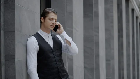 Businessman using a smartphone to talk about business. Standing on the sidewalk Stock Footage 129885707