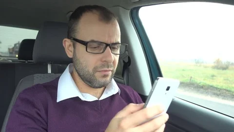 Businessman using a smartphone while sitting inside car. Man with a smart-pho Stock Footage 84720373