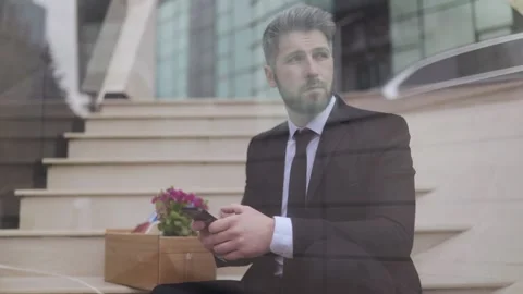 Businessman using smartphone while sitting outside an office building Video stock 307187487