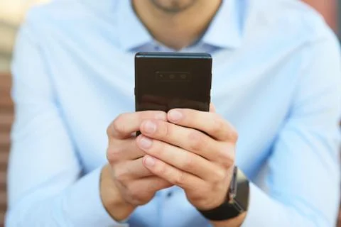 Businessman using smartphone while sitting on the bench outdoors, focus on Foto stock