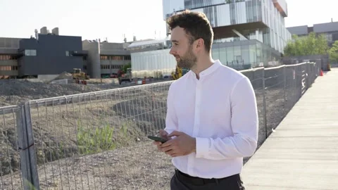 Businessman using smartphone while walking near construction area. Stock Footage 244246175