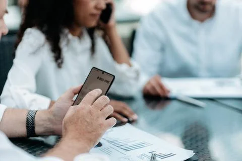 Businessman using a smartphone while working with financial docu Stock Photos