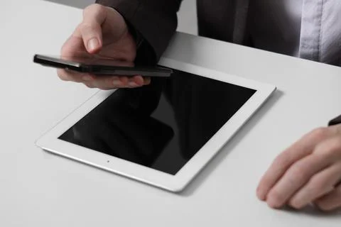 Businessman using smartphone at white table with tablet, closeup. Modern te.. 库存照片