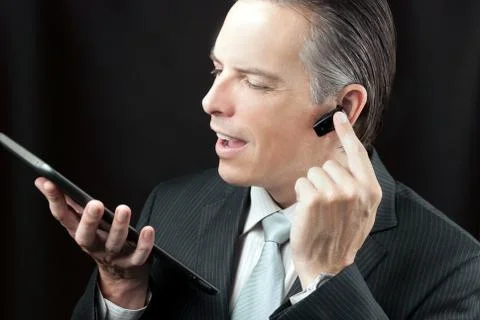 Businessman using tablet adjusting headset earpiece. Stock Photos