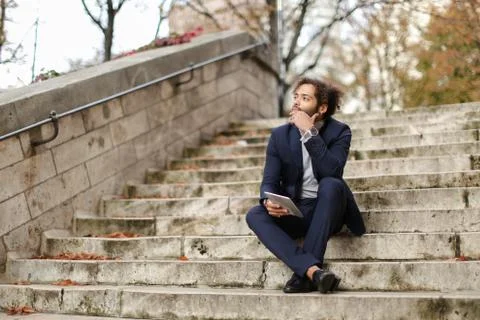 Businessman using tablet and sitting on steps. Stock Photos
