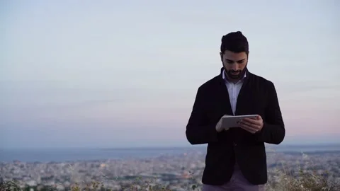 Businessman using tablet and working with sunset skyline in background Stock Footage 133376025