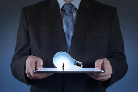 Businessman using tablet computer growing  light bulb as concept 스톡 일러스트