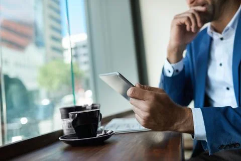 Businessman using a tablet over coffee in a cafe Stock Photos